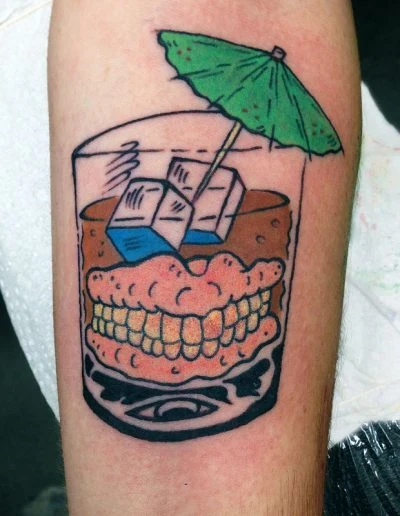 Novelty whisky glass and teeth tattoo on a leg